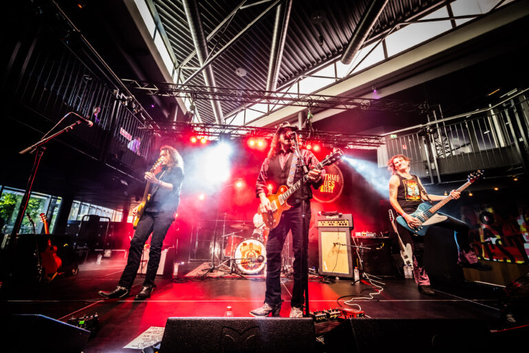 Een rockband geeft een liveoptreden op een podium met kleurrijke verlichting.
