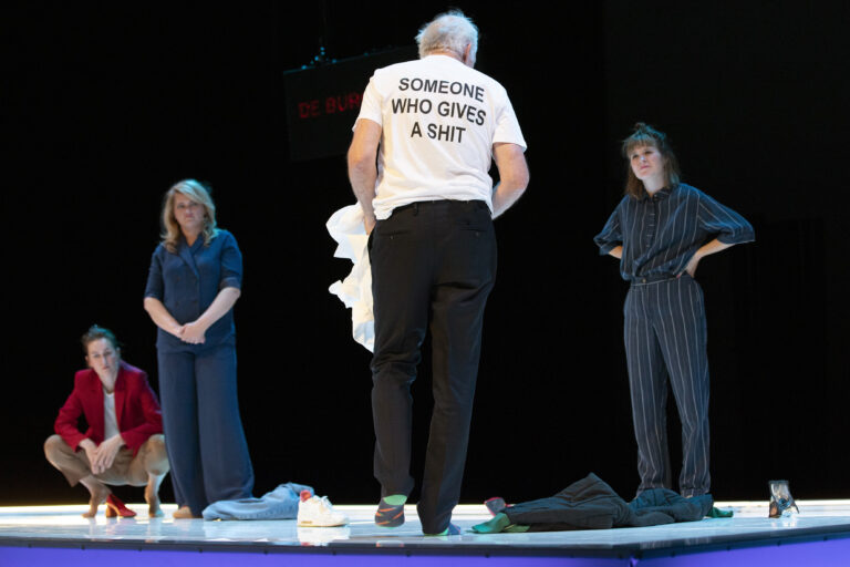 Een groep acteurs op een podium, waarvan één persoon een T-shirt met de tekst
