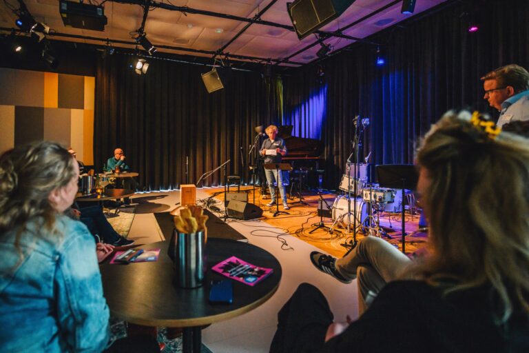 man staat te praten voor publiek met microfoon