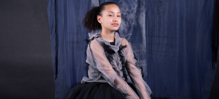 Meisje met paarse kleding met een paarse achtergrond kijkt heel stoer naar de camera