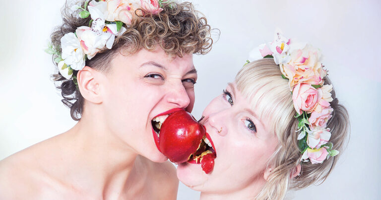 Twee leden met bloemen in het haar eten samen een appel