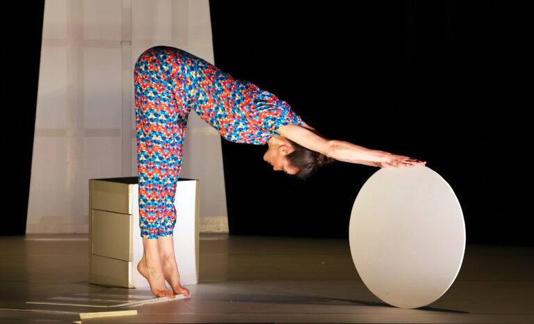 Danser staat met haar bovenlichaam naar beneden en strekt zich uit op een groot nagemaakt ei