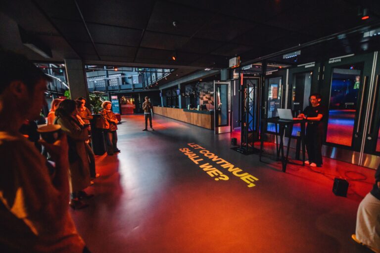 Een moderne ontvangstruimte met bezoekers die wachten, en verlichting die de vloer verlicht met tekst.