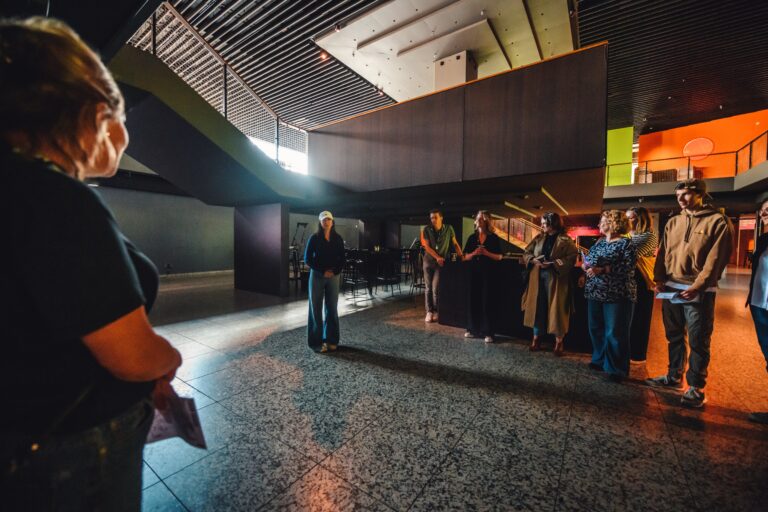 Een groep mensen staat in een moderne ruimte met hoge plafonds en natuurlijke verlichting.