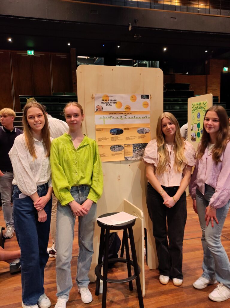 Vier mensen staan voor een presentatiebord in een binnenruimte.