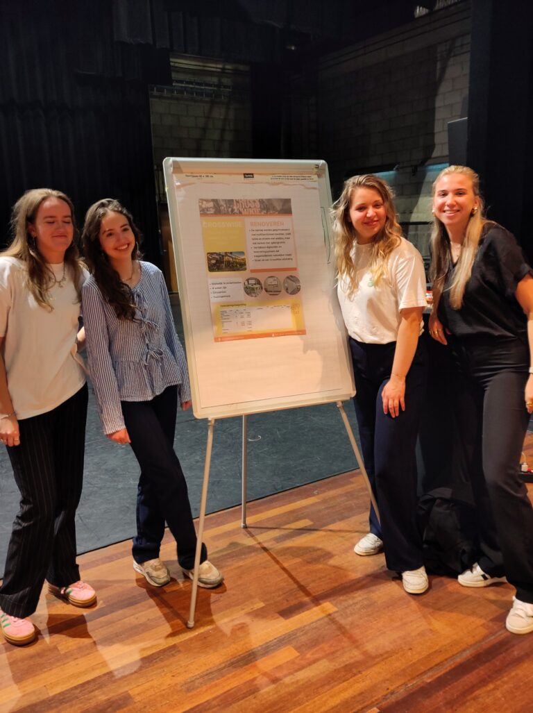 Vier mensen poseren naast een posterbord op een ezel.