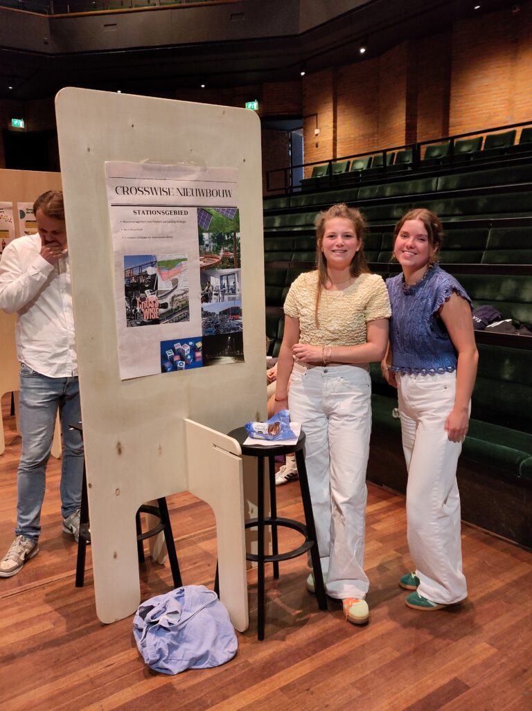 Twee vrouwen staan naast een informatiebord in een overdekte ruimte.