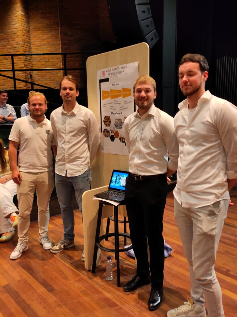 Vier mannen poseren naast een presentatieposter op een evenement.
