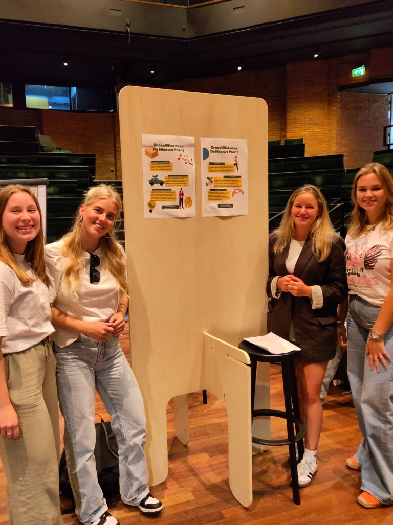 Vier mensen staan naast een tentoonstellingsbord in een binnenruimte.