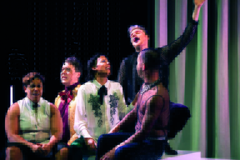 Vijf personen in feestelijke kleding zitten bij elkaar en zingen