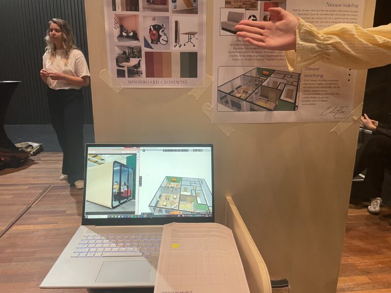 Laptop met architecturale tekeningen op het scherm, opgesteld voor een tentoonstellingspaneel met foto's en illustraties.