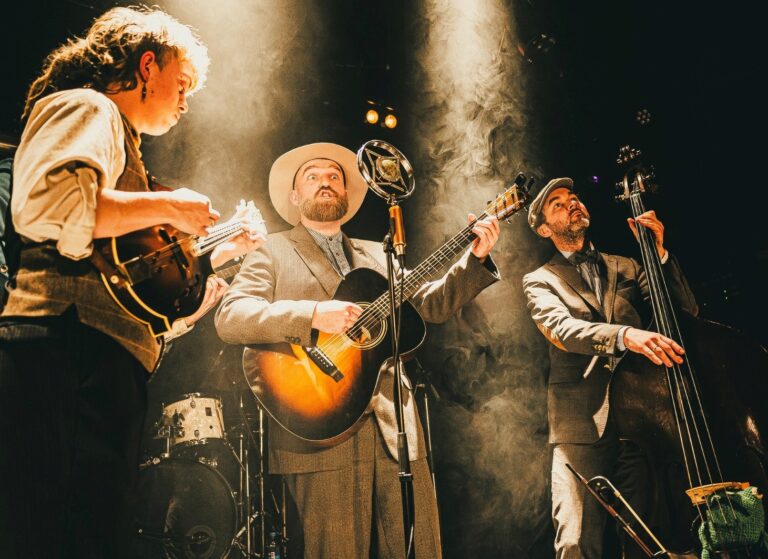 foto van onderen van vier mannen met gitaar aan het optreden