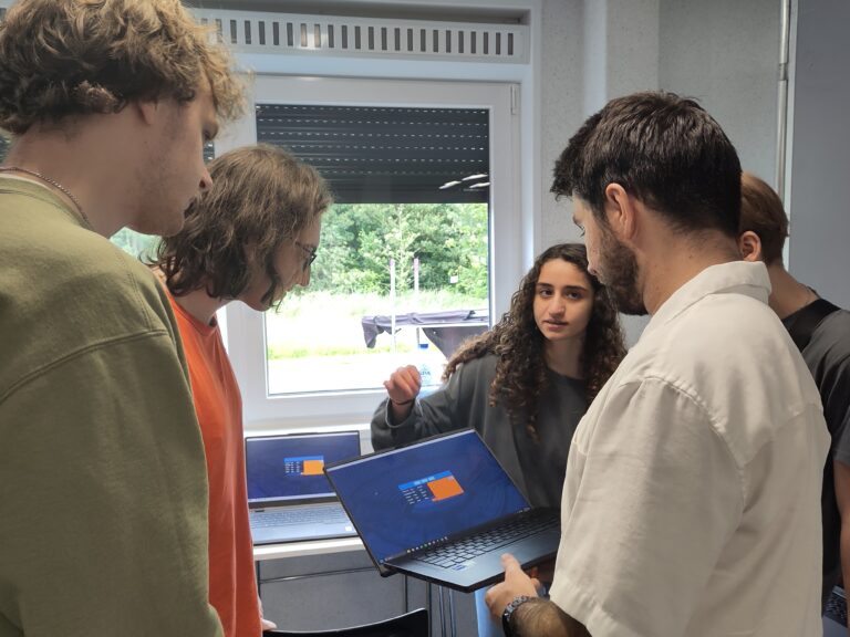 Vier mensen bespreken een presentatie in een kantoor.