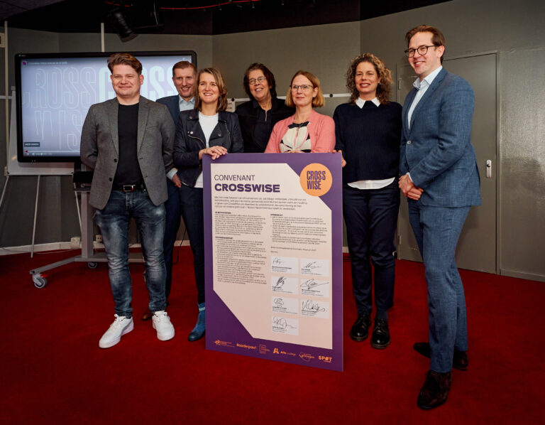 Een groep mensen poseert voor een foto terwijl ze een groot bord vasthouden met tekst en handtekeningen erop.