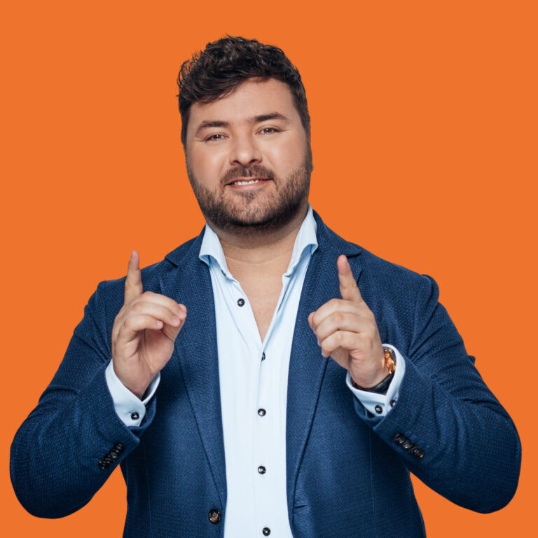 Man in een blauw pak tegen een oranje achtergrond.