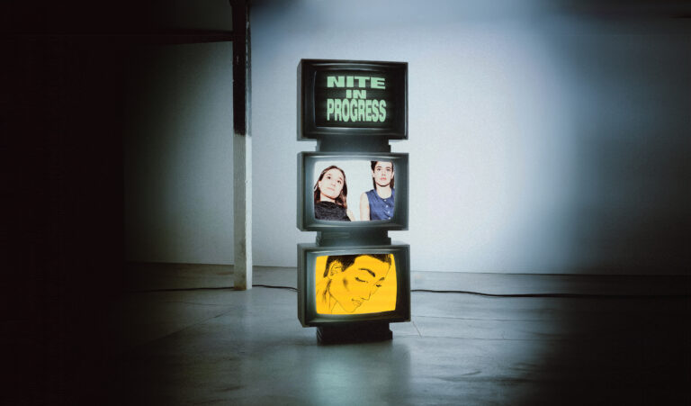 Grijze ruimte met een zuil waarop drie schermen te zien zijn