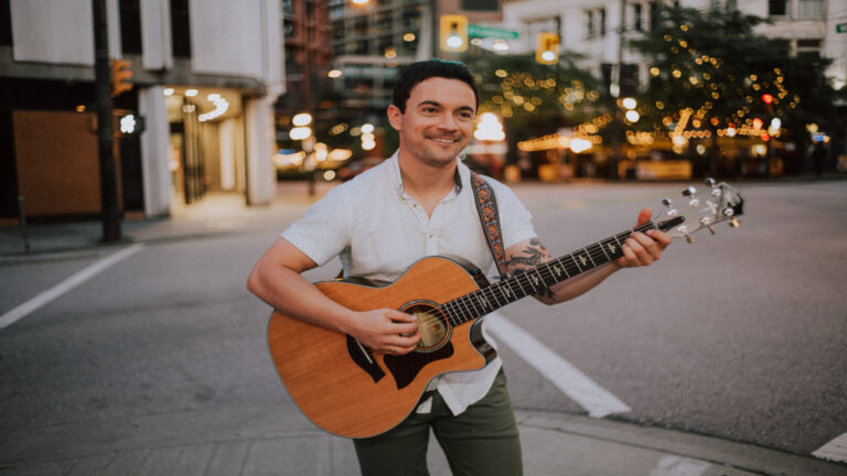Een man met een wit overhemd en een gitaar.