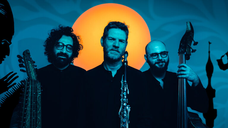 Steven Kamerman, Hamid Reza Behzadian en Esat Ekincioğlu staan voor het decor van de film The adventures of prince achmed. In de achtergrond is een zon te zien.