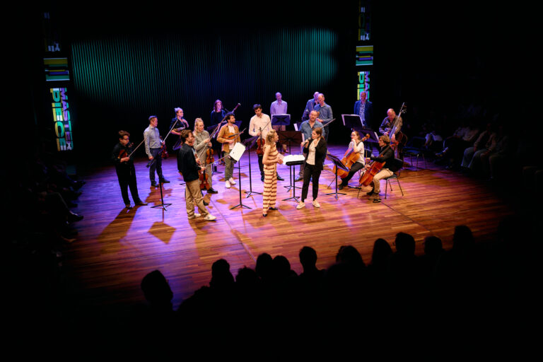 deel van het orkest die samen met een presentatrice wat uitlicht over het stuk