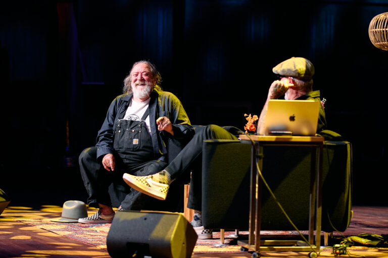 twee lachende mannen die op een podium een voorstelling geven