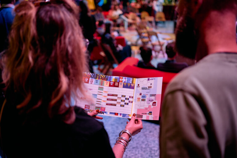 Man en vrouw kijken naar het programma boekje van Masterpiece 2024