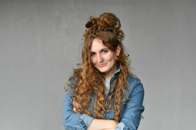 Lisanne Dijkstra staat lachend voor een grijze muur