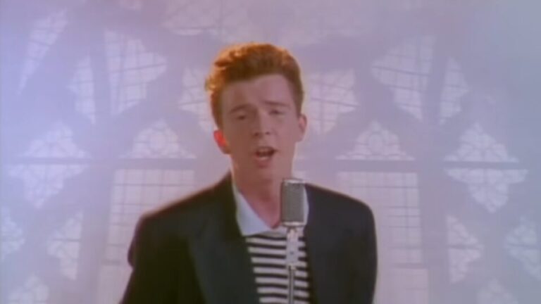 Een man zingt in een microfoon met een glas-in-lood raam op de achtergrond.