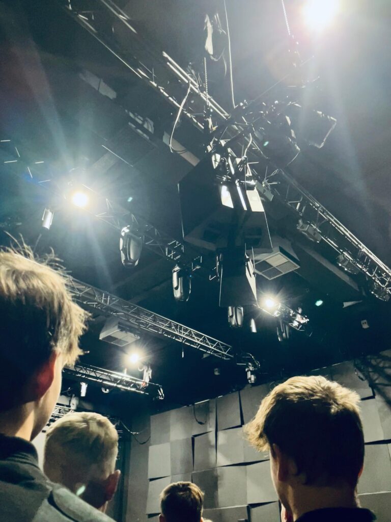 foto in kikvorsperspectief waar omhooggekekenn wordt vanuit een groep studenten naar het plafond met alle lichtopstellingen.