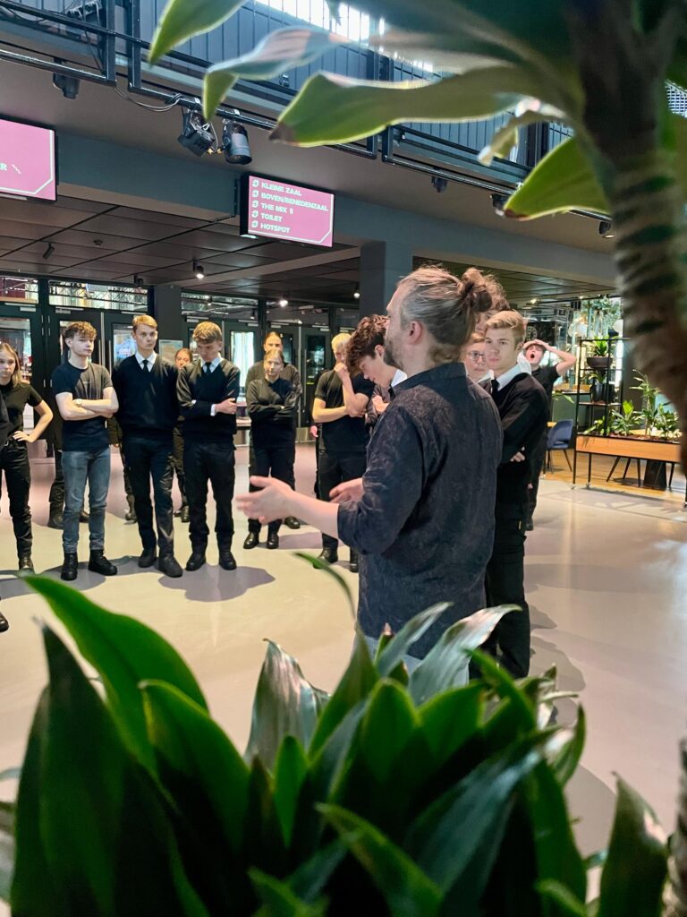 Foto van een uitleg waarbij een groep aandachtig aan het luisteren is naar de man die voor hun staat