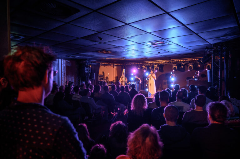 Een optreden op een podium met kleurrijke verlichting, terwijl een publiek toekijkt.