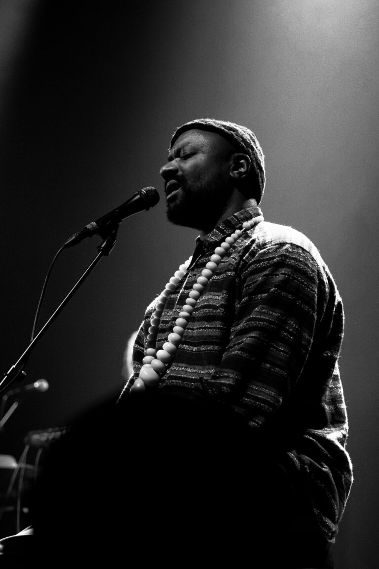 Een singer-songwriter performt live op het podium met een microfoon en een mooie achtergrondverlichting.