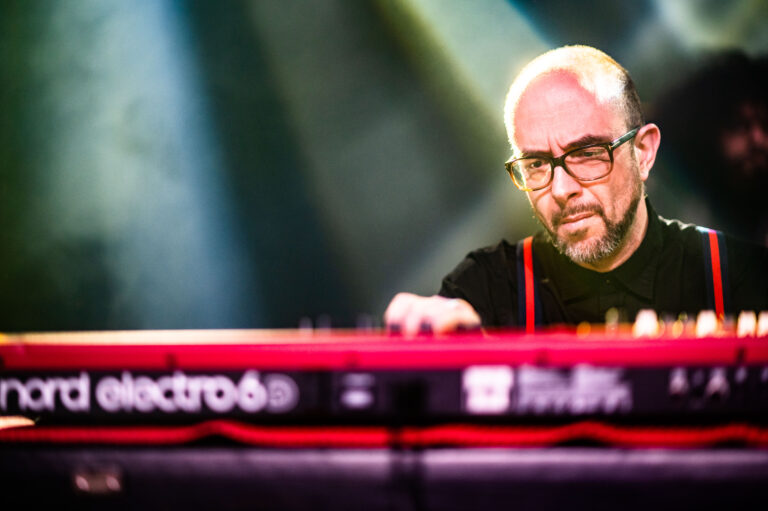 Een muzikant speelt op een keyboard met verlichting op de achtergrond.