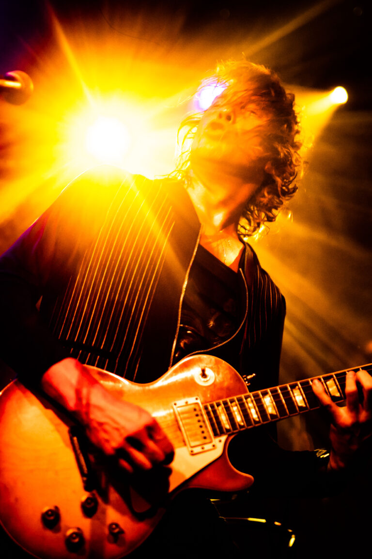 Een muzikant speelt gitaar, omringd door een stralend licht.