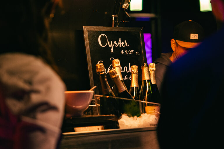 Een bar met flessen champagne en een bord met de tekst