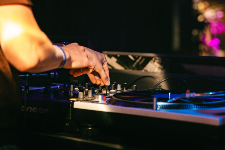 Een close-up van een hand die draait aan de knoppen van een dj-console.