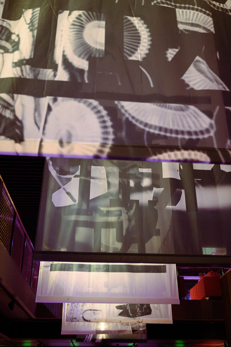 Abstracte geprojecteerde beelden op doorzichtige doeken in een interieur met gedempte verlichting.