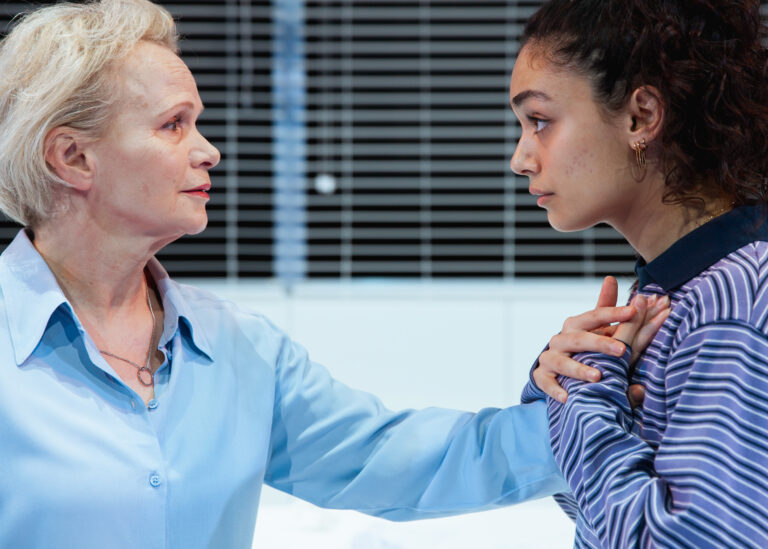 Twee vrouwen hebben een intense conversatie in een moderne, goed verlichte ruimte.