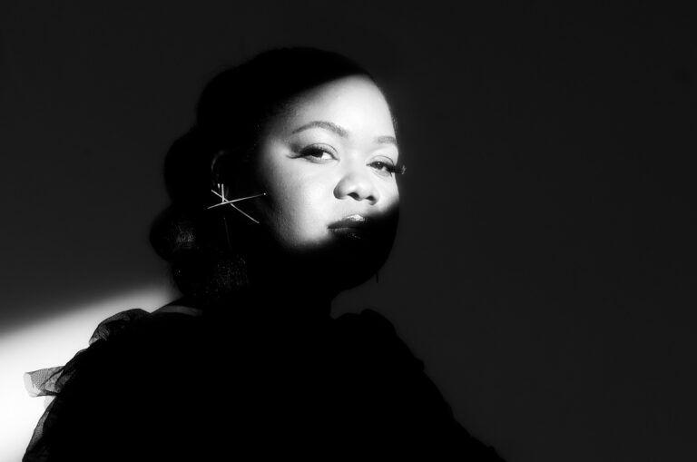 Portret van een vrouw met een dramatische schaduweffect en een stralende lichtstraal op haar gezicht.