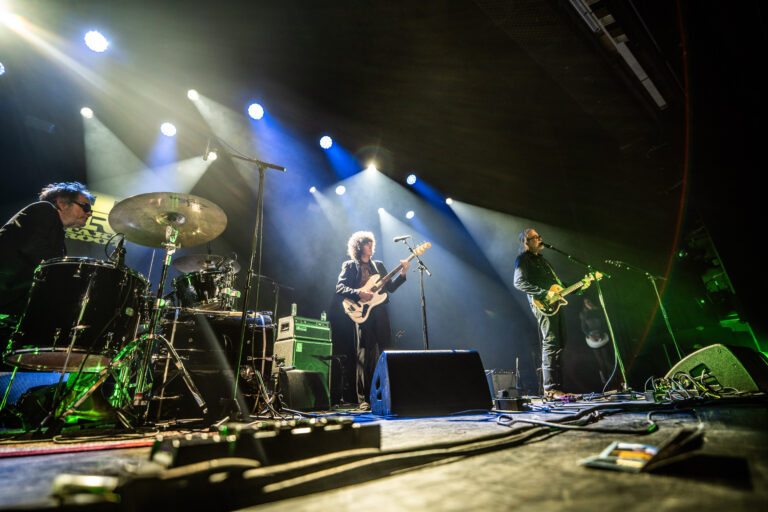 Een band speelt live op een podium met kleurrijke verlichting.
