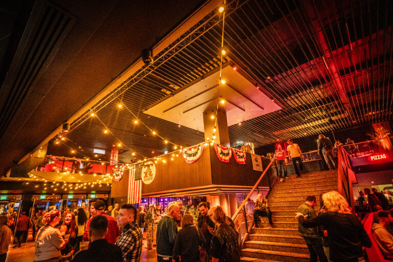 Een drukke avondlocatie met sfeervolle verlichting en decoraties in festivalstijl.