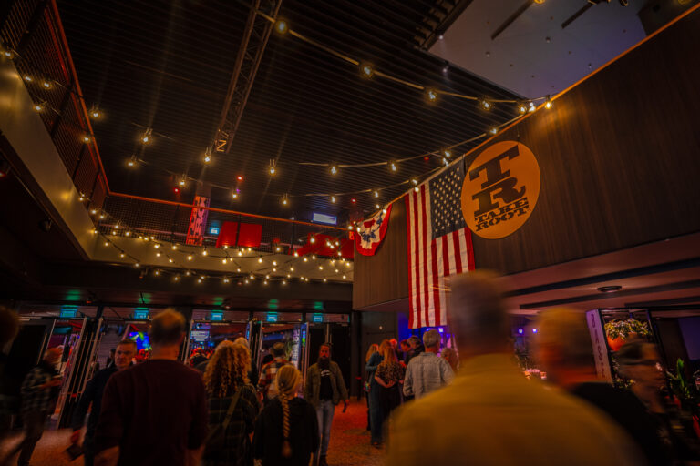 Een drukke ruimte met sfeervolle verlichting en een Amerikaanse vlag op de muur.