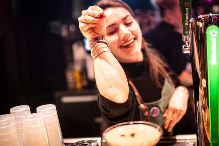 Een blije bartender die een drankje bereidt achter de bar.