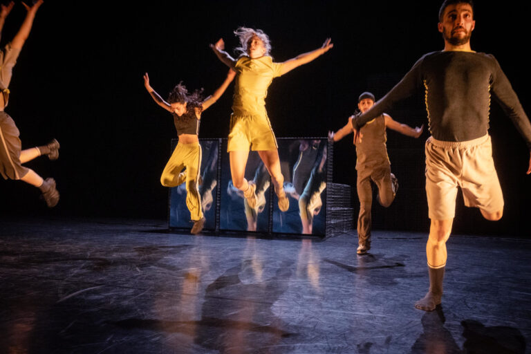 De performers springen in de lucht met armen omhoog