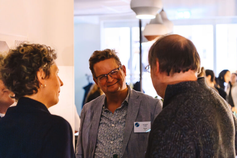 Drie mensen in gesprek in een lichte, moderne omgeving met gevuld interieur.