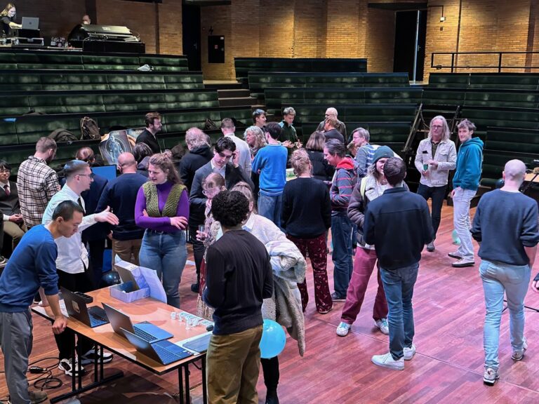 Een drukke zaal met mensen die met elkaar praten en verschillende activiteiten ondernemen.