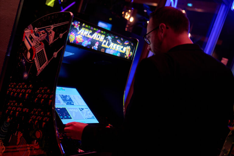 Een persoon speelt een vintage arcade spel met een scherm dat