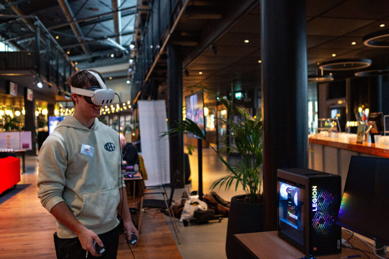 Een man met een mondkapje loopt langs blauwe kolommen in een moderne zaal met warme verlichting.