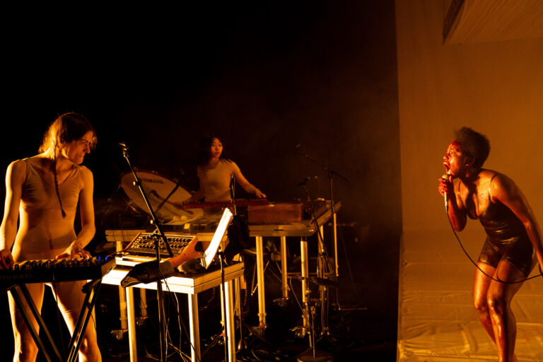 Donkere nacht scène met een houten podium en een groep mensen eromheen.