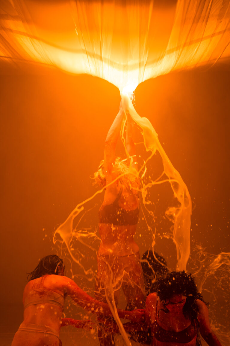 Een fel oranje achtergrond met een smalle, verticale lichtgevende vorm in het midden.