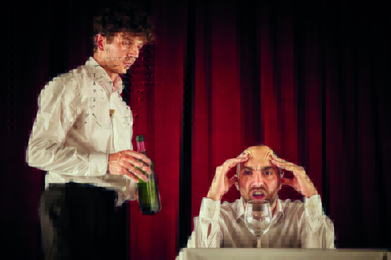 Twee mannen in formele kleding staan in een dramatische setting; één houdt een fles vast terwijl de ander gefrustreerd zijn hoofd vasthoudt.